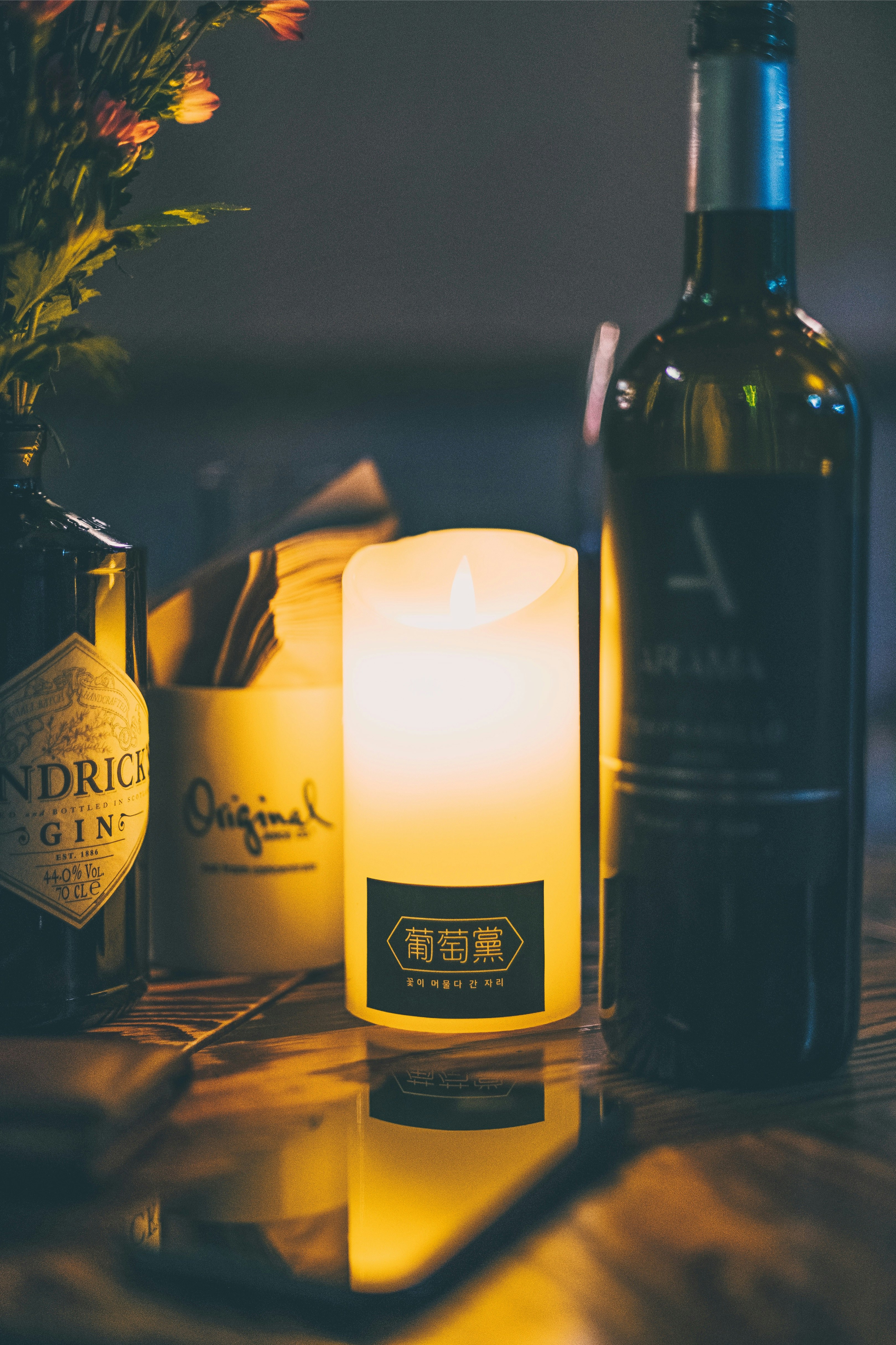 white pillar candle beside wine bottle
